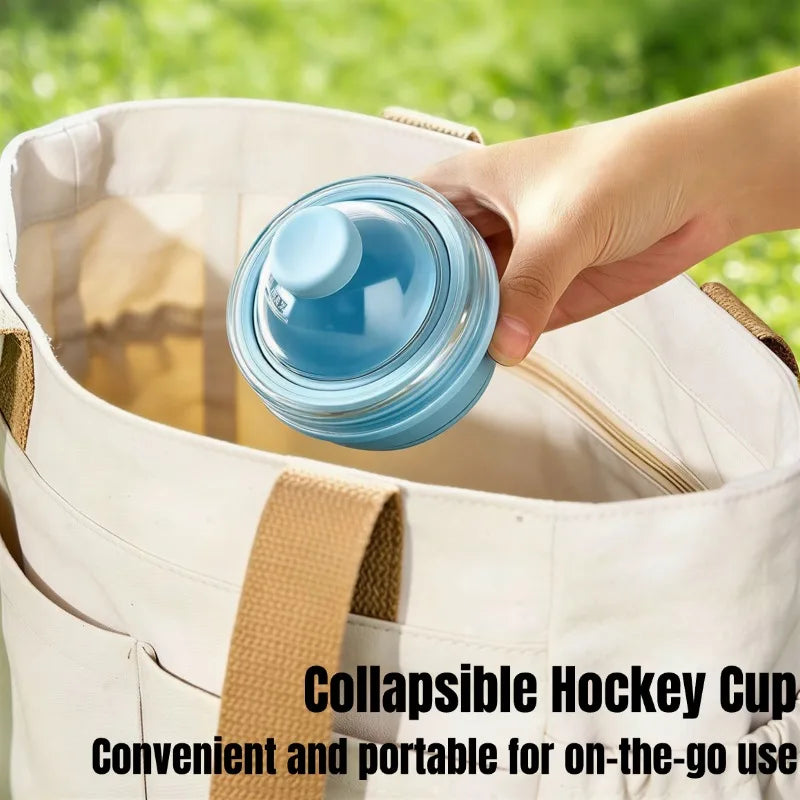 Collapsible hockey cup being placed into a bag with a green outdoor background