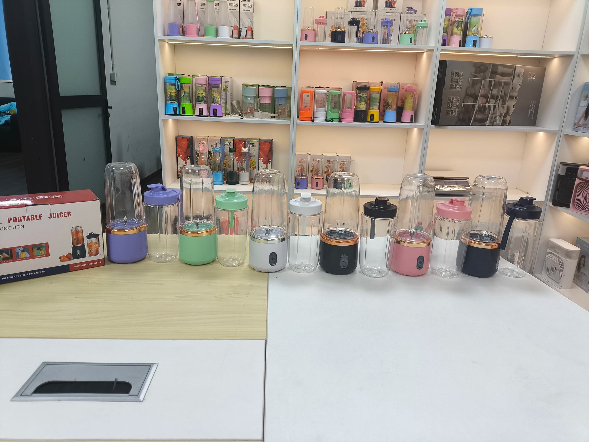 Collection of portable juicers on a counter with shelves in the background.